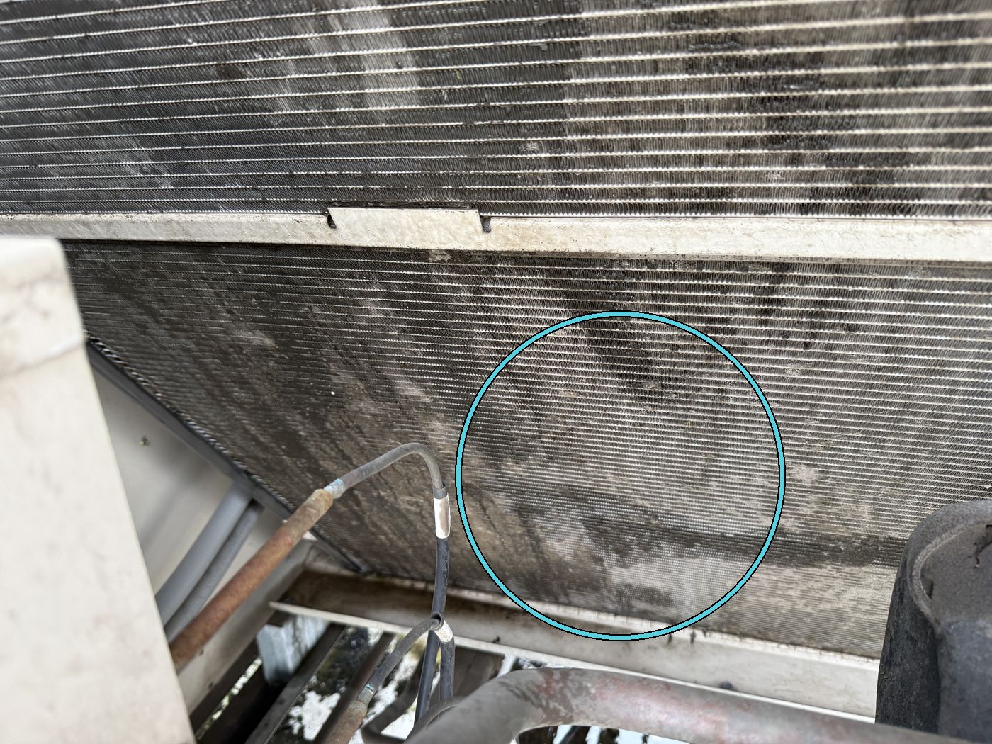 Lower condenser coil with dark oily staining near the bottom